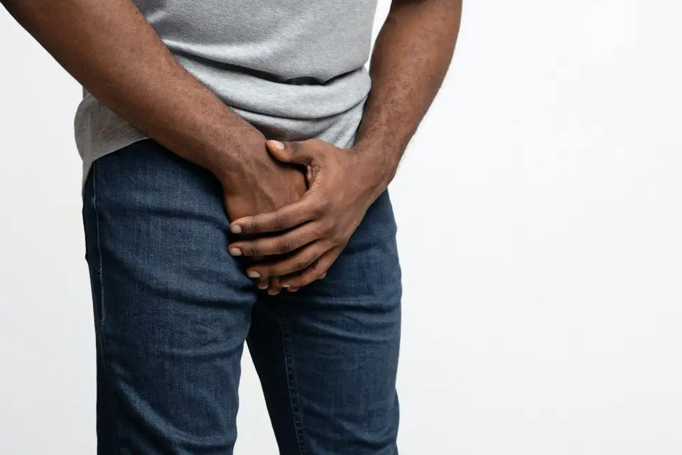 Cropped of black guy holding his groin