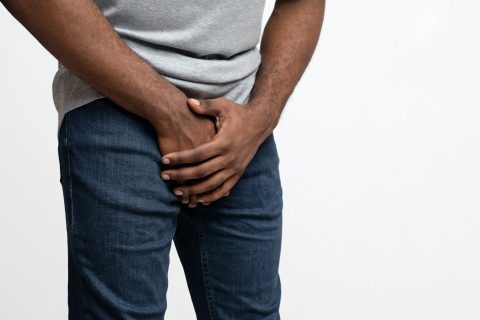 Cropped of black guy holding his groin